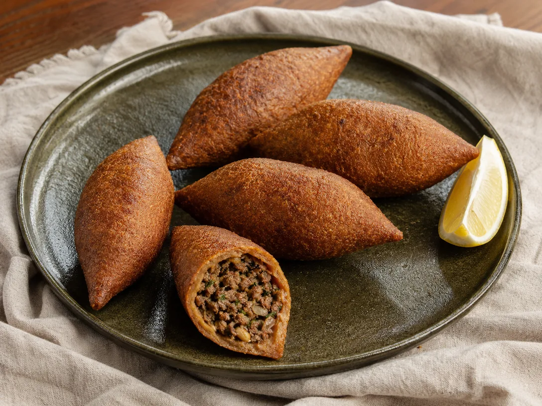 Yeşil seramik tabakta ikiye bölünmüş ev yapımı içli köfte ve limon dilimi